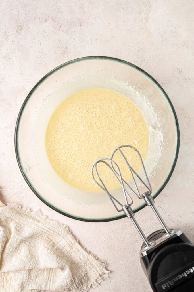 The wet ingredients mixed together in a glass bowl with electric beaters.