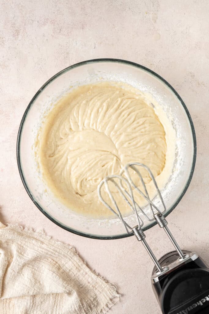 Mixing together the cupcake batter in a glass bowl with electric beaters.