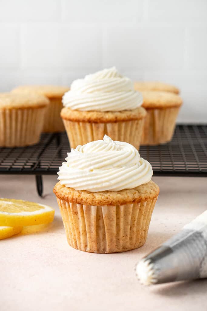 Piping swirls of lemon buttercream frosting onto lemon cupcakes.