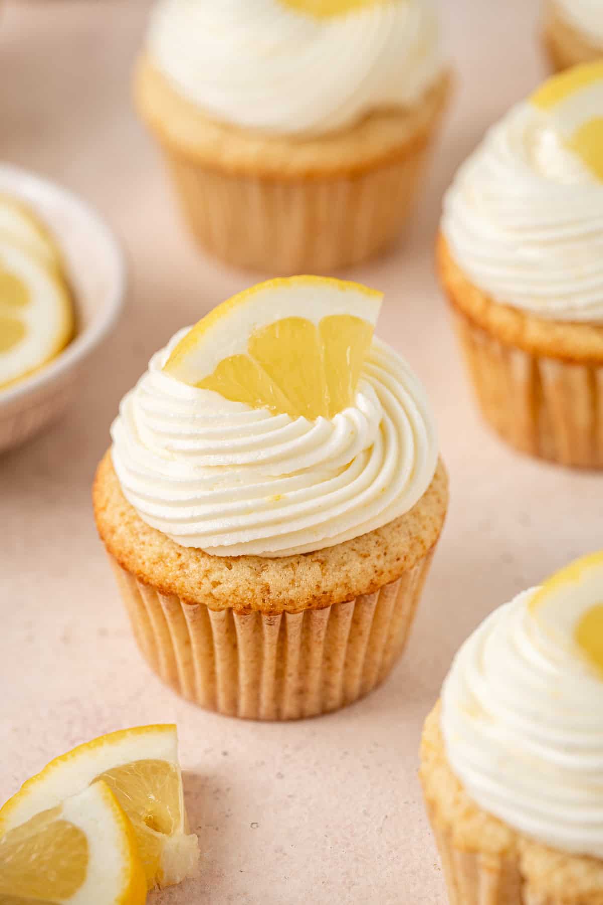 Dairy and gluten free lemon cupcakes with buttercream frosting, topped with a wedge of fresh lemon.