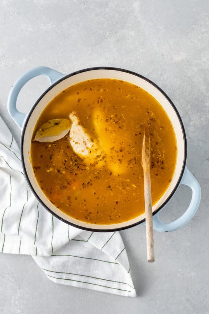 Adding the liquid and chicken to the pot to cook.