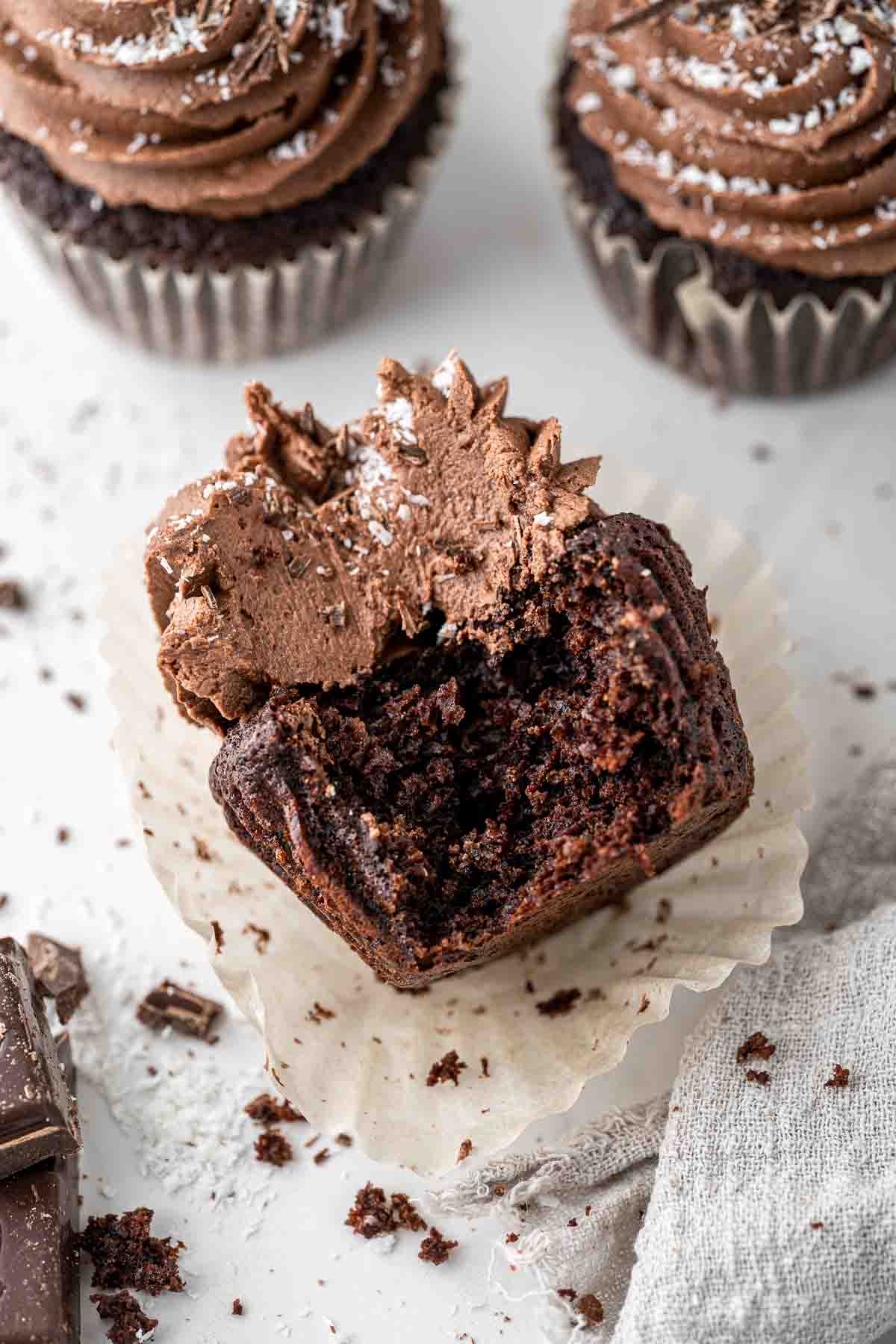 Close up of a chocolate and coconut cupcake with a bite taken.