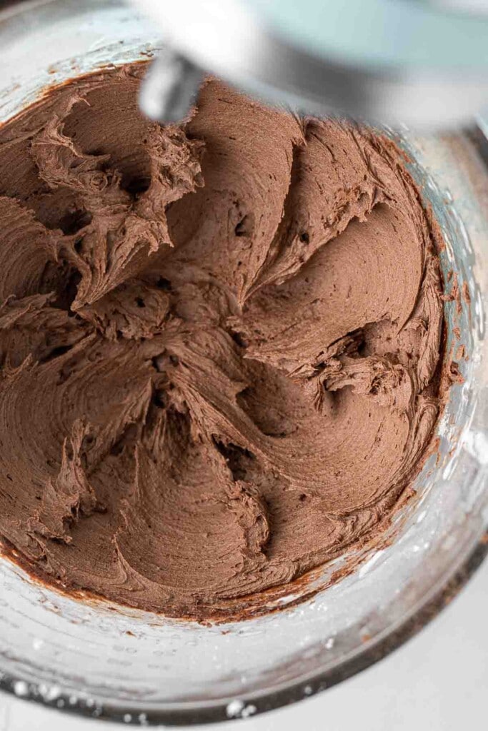 Close up of chocolate buttercream in the bowl of a stand mixer.