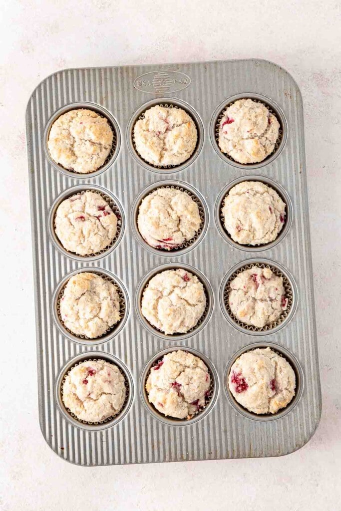 Freshly baked raspberry and coconut muffins in a baking tray.