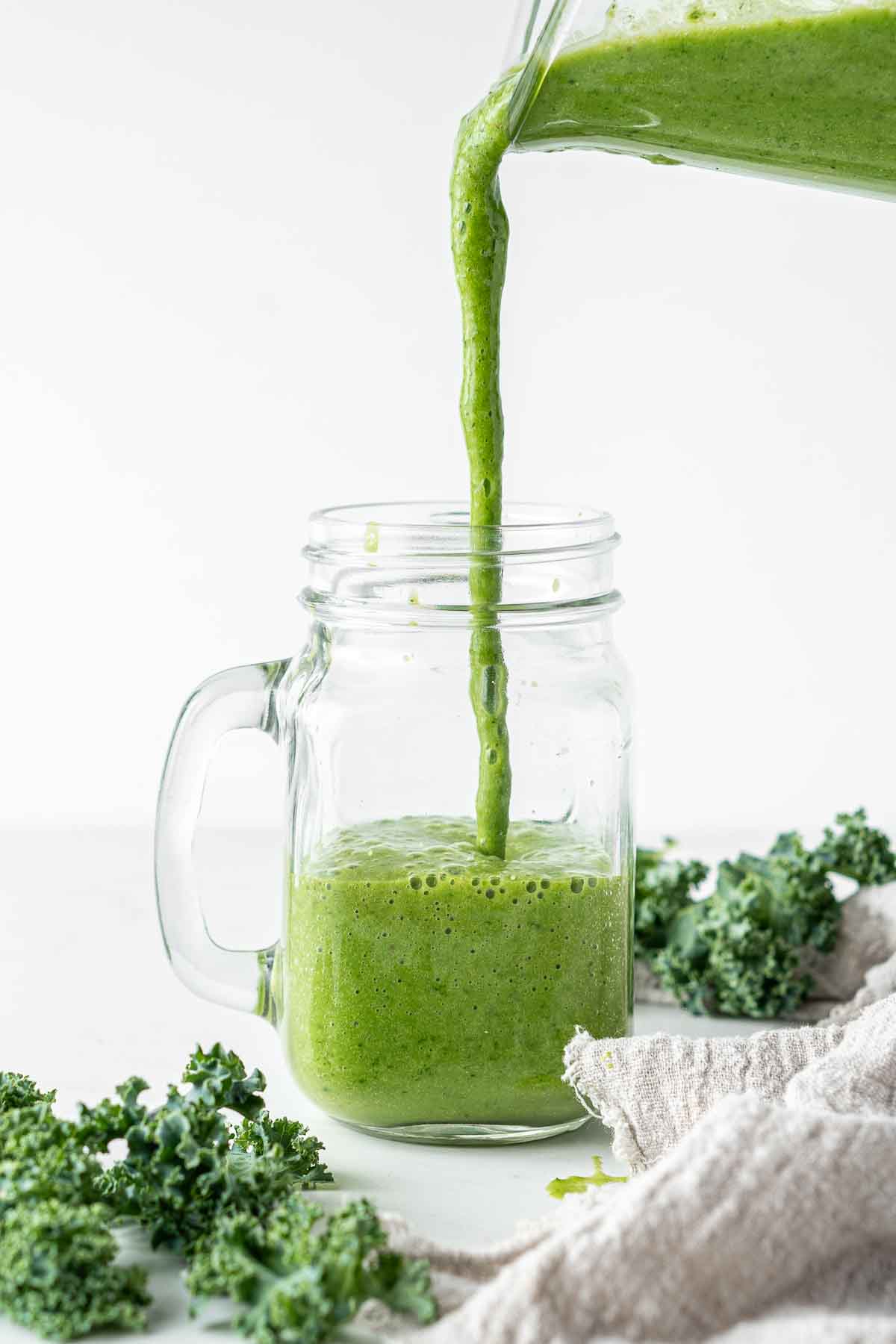 Mango kale smoothie being poured into a glass. 