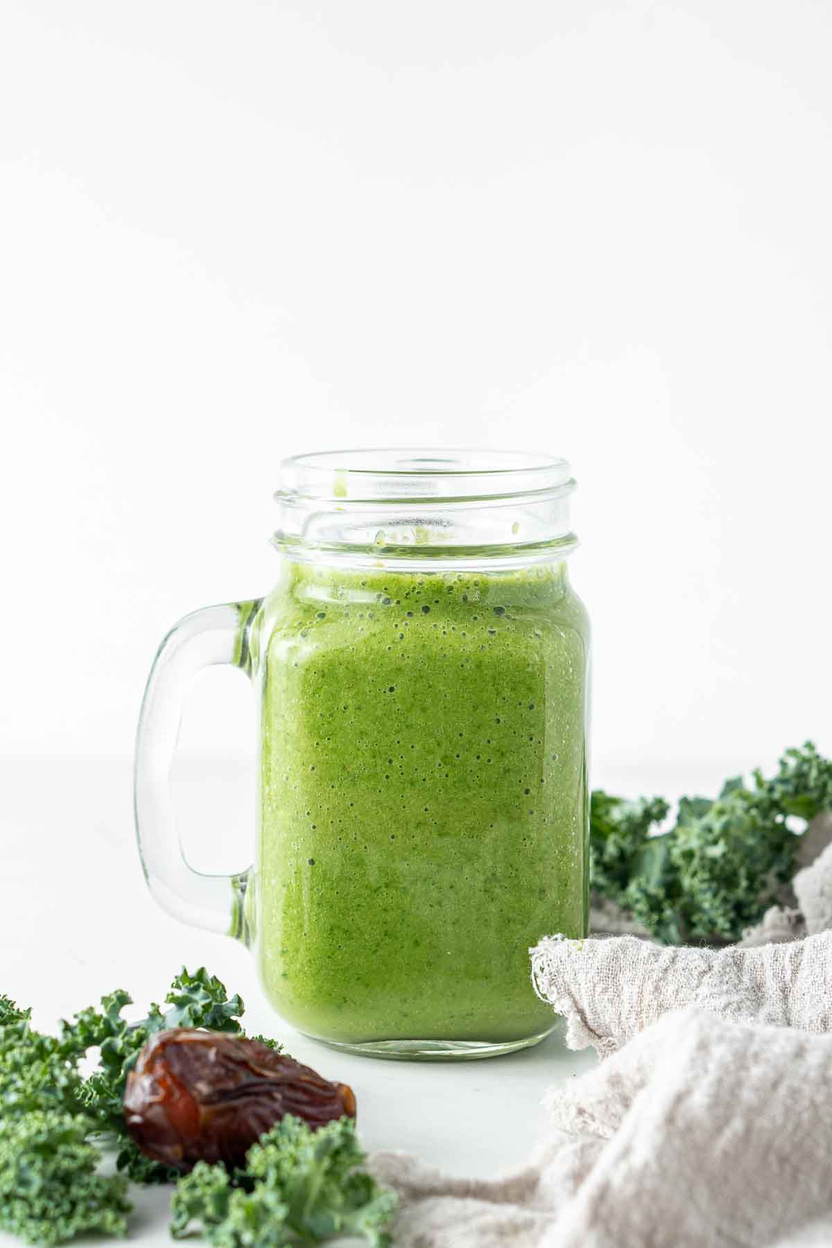 Mango and kale smoothie served in a glass with a handle.