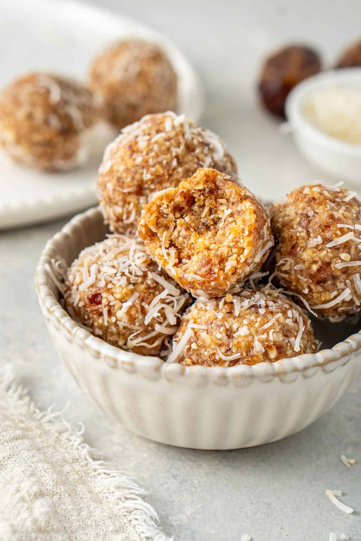 A close up of the peanut butter balls in a bowl one with bite taken.