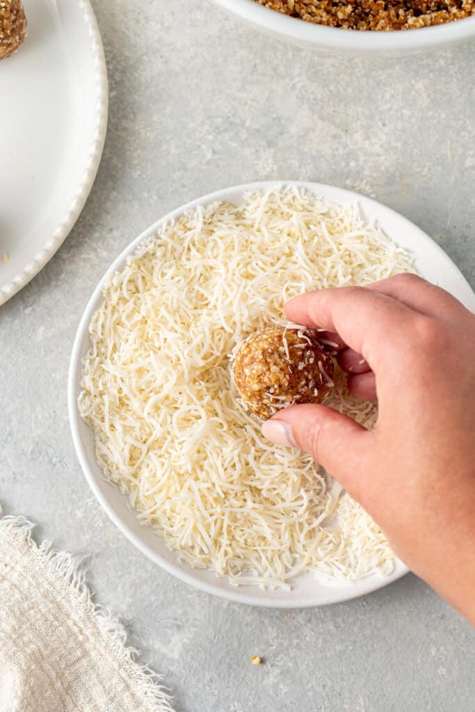 Rolling balls of mixture in extra coconut.