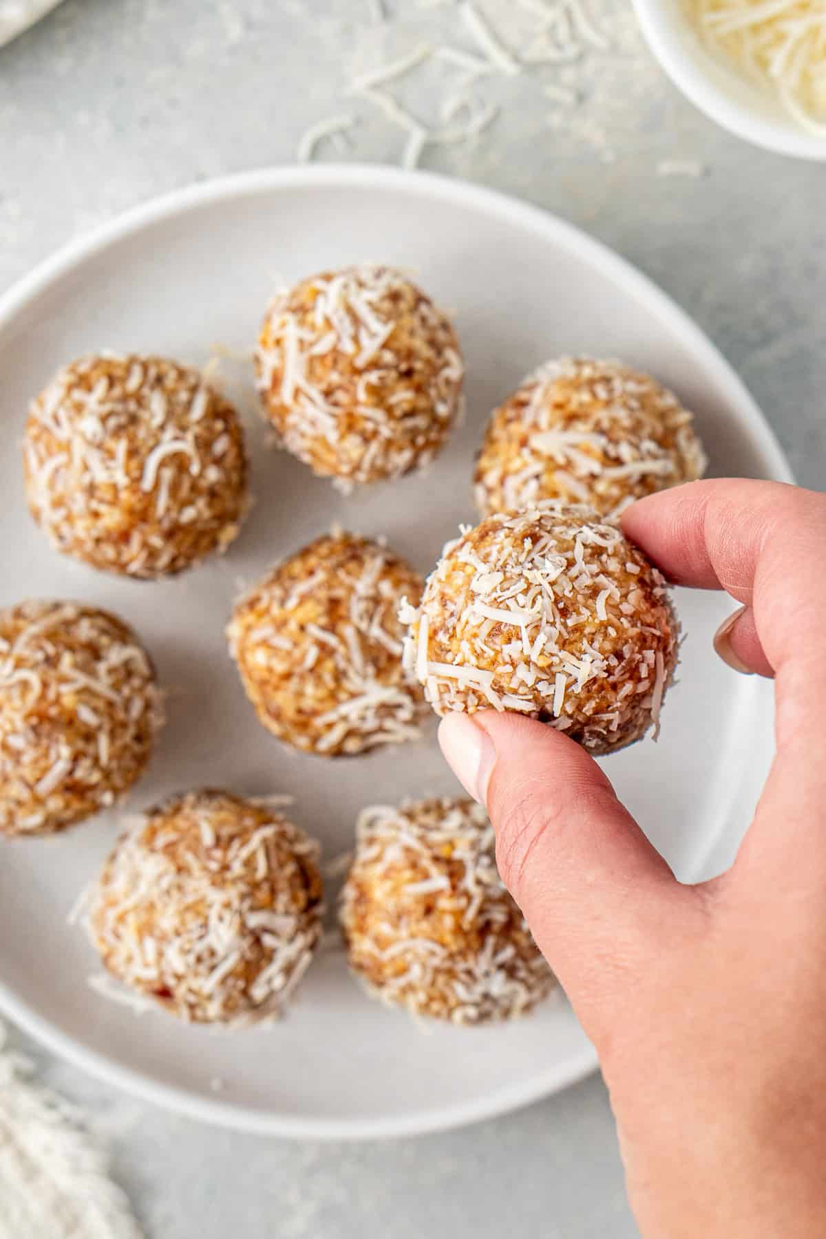 A hand picking up a peanut butter ball from a plate.