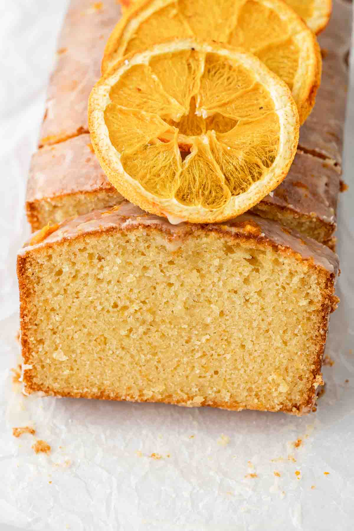 Close up of a slice of orange pound cake topped with dehydrated orange. 