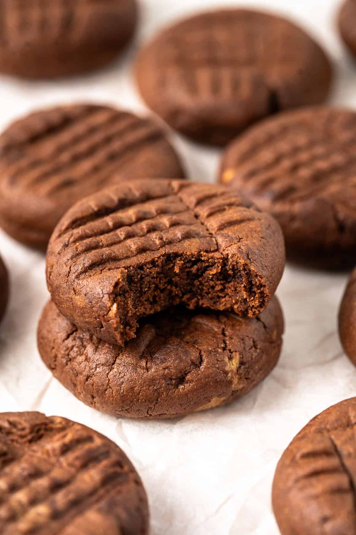 Two dairy free chocolate peanut butter cookies stacked on top of each other. One has a bite taken.