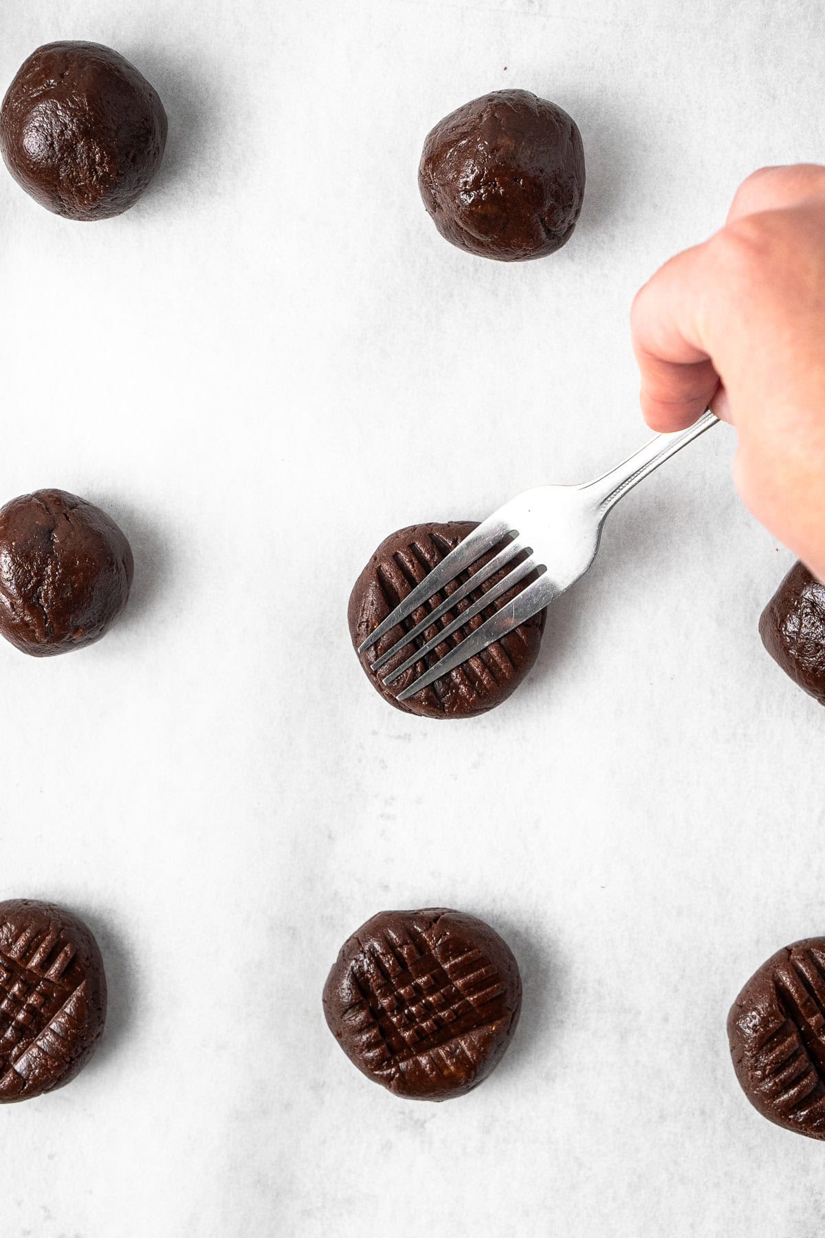 Pressing each ball down with a fork.