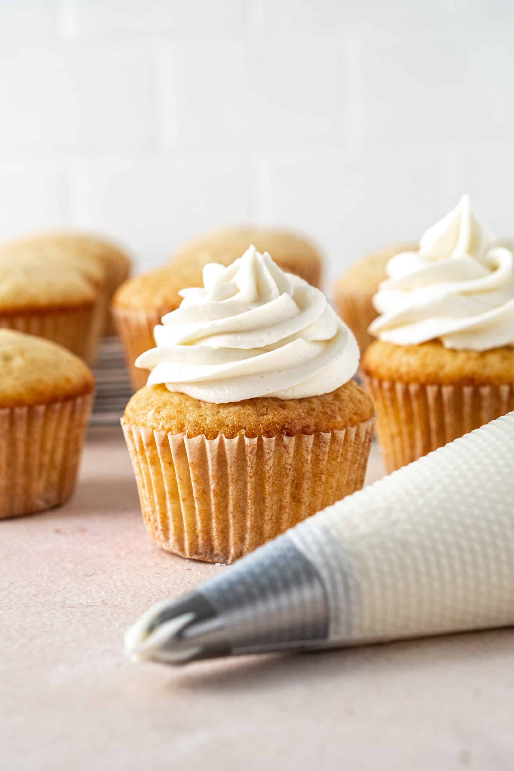 A piping bag and a cupcake with dairy free vanilla buttercream.