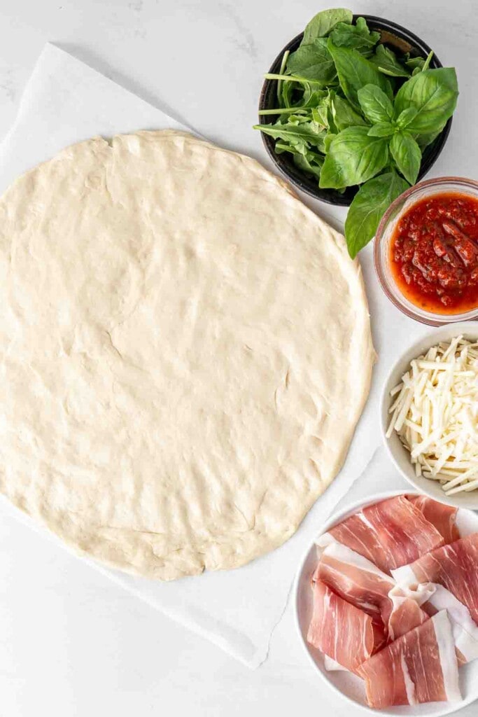 Pizza dough rolled out with all toppings on the side.