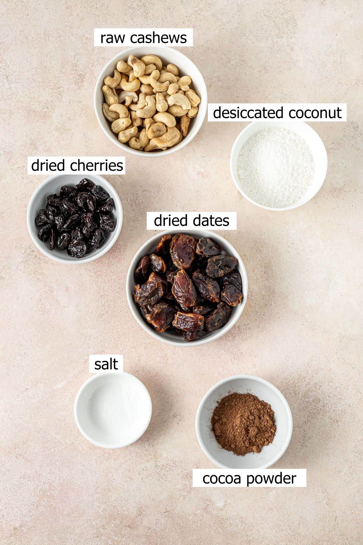 All ingredients needed to make cherry ripe bliss balls laid out in small bowls. 