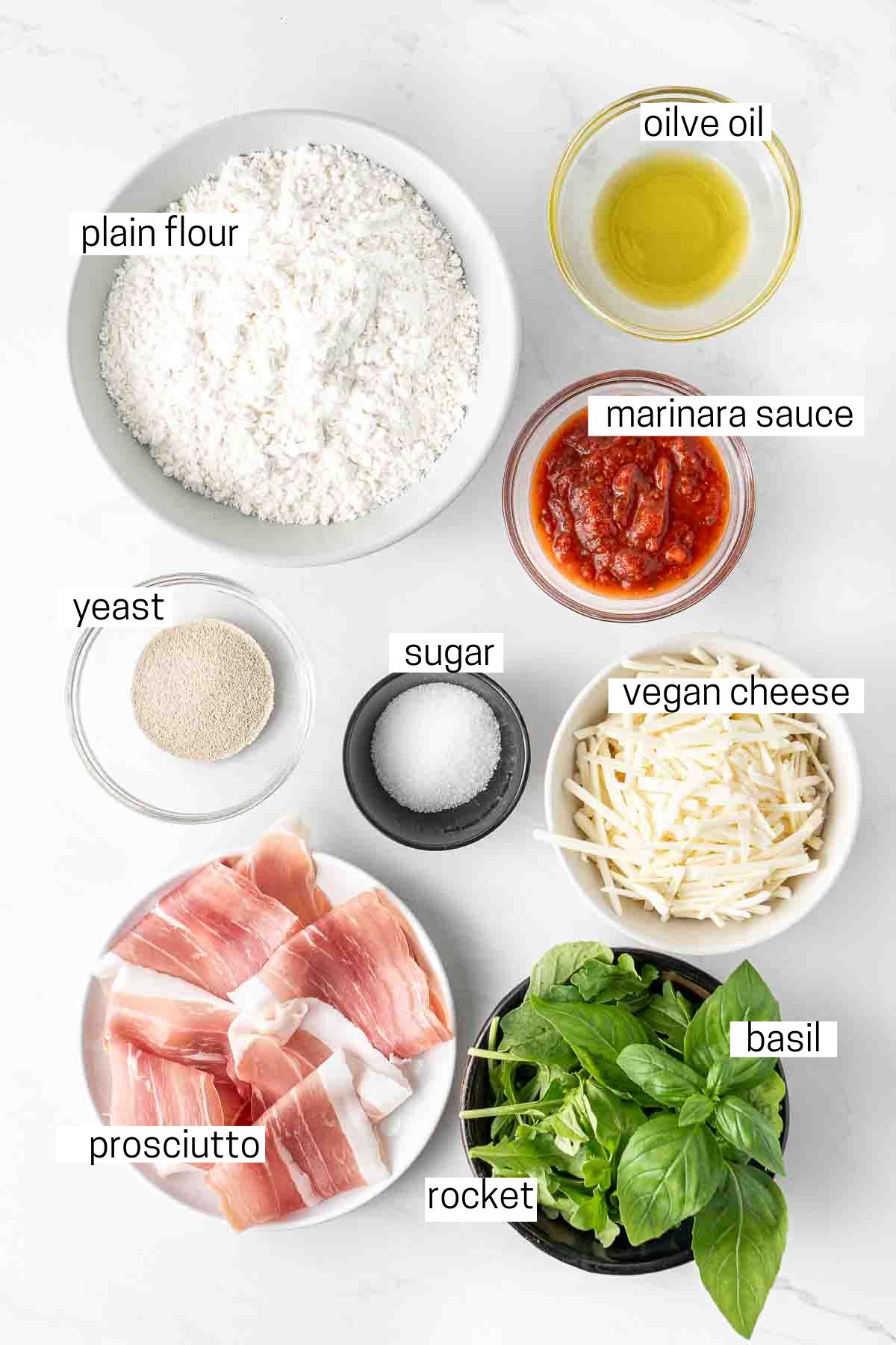 All ingredients needed to make prosciutto pizza laid out in small bowls.