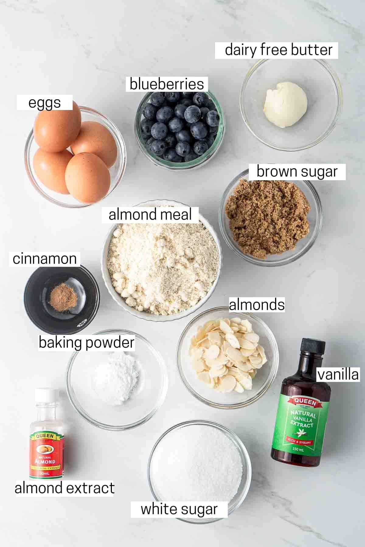 All ingredients needed for blueberry almond cake laid out in small bowls.