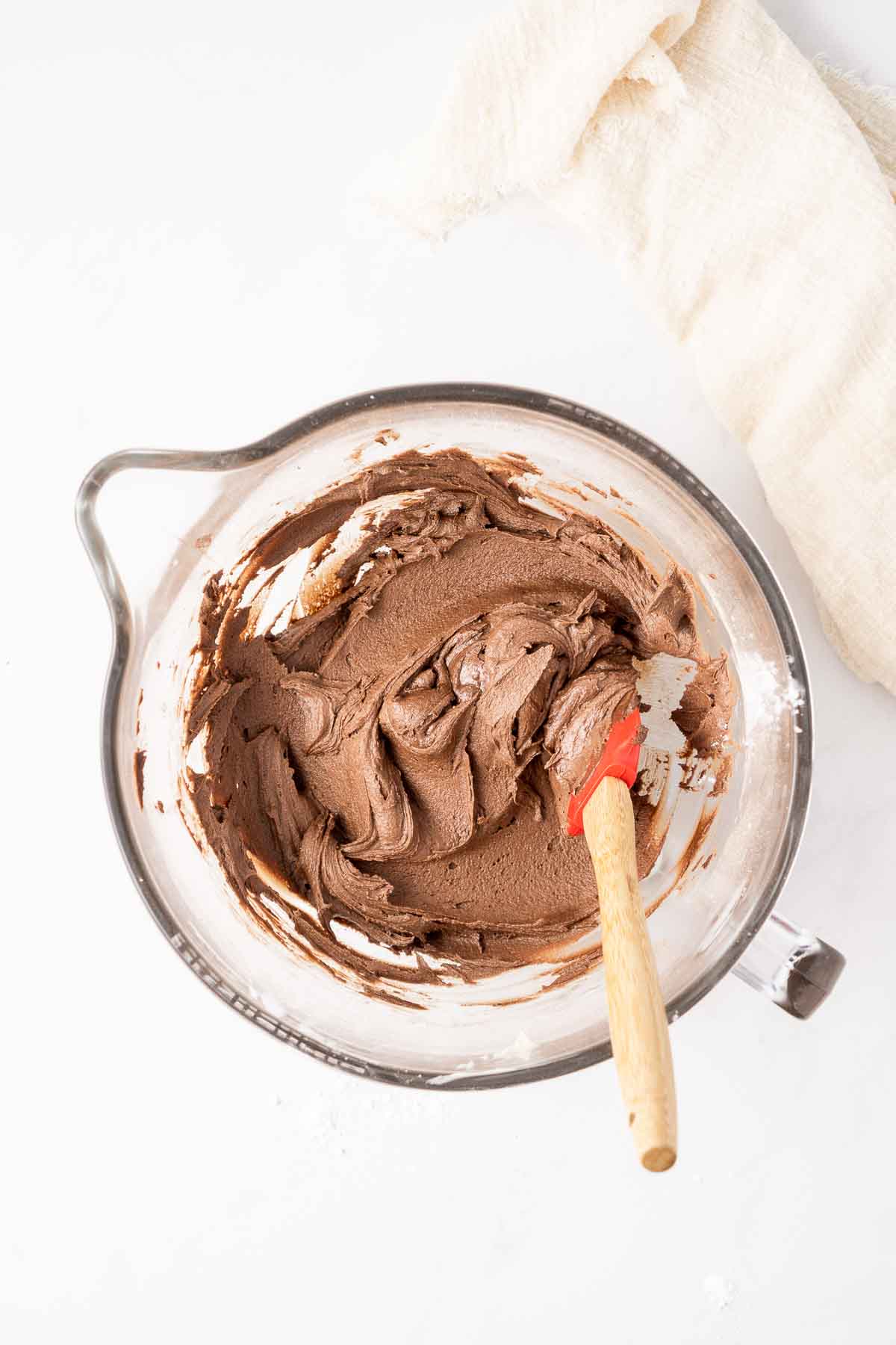 Vegan chocolate buttercream in a bowl with a red spatula. 