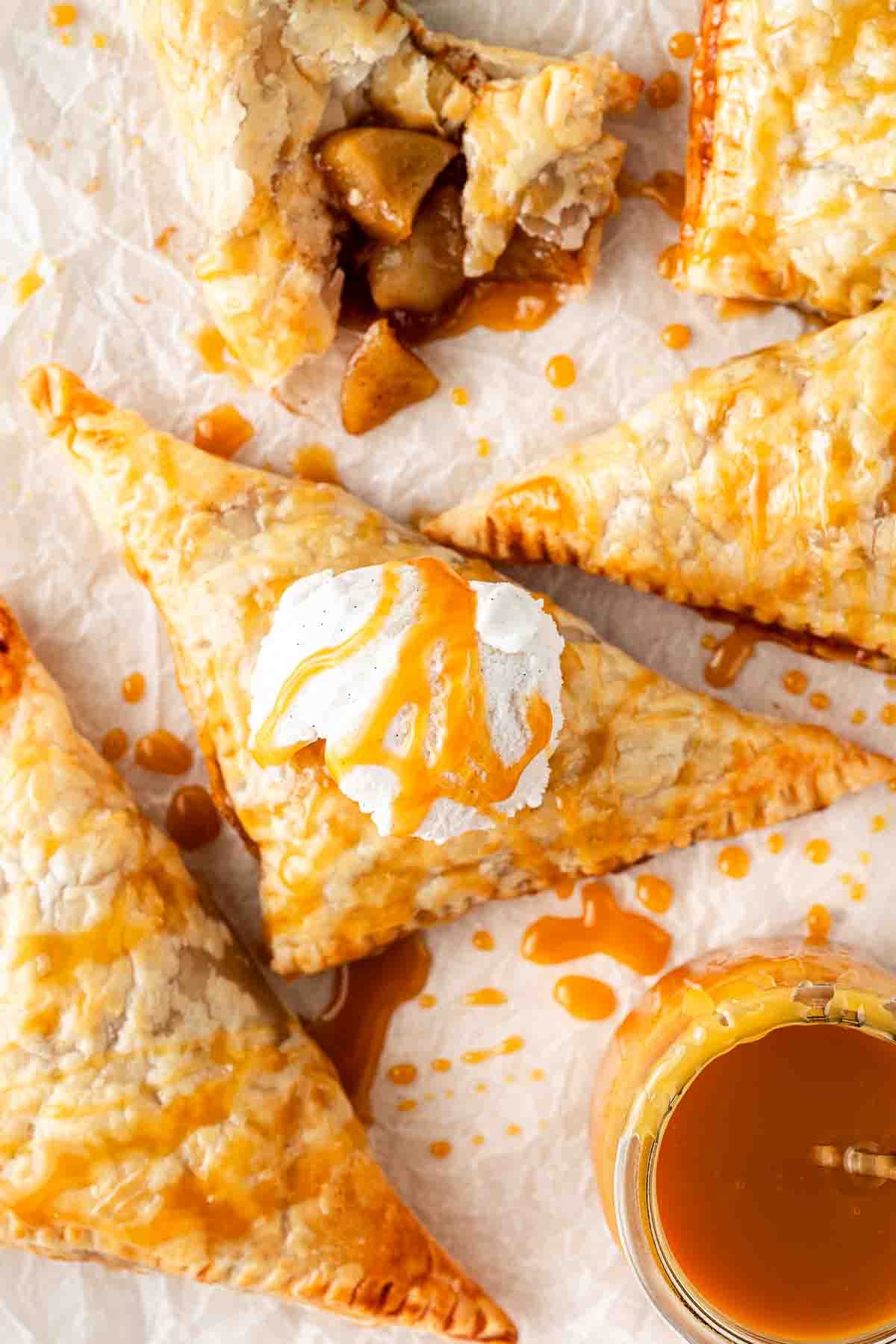 Apple turnovers on a plate with ice cream and caramel sauce.