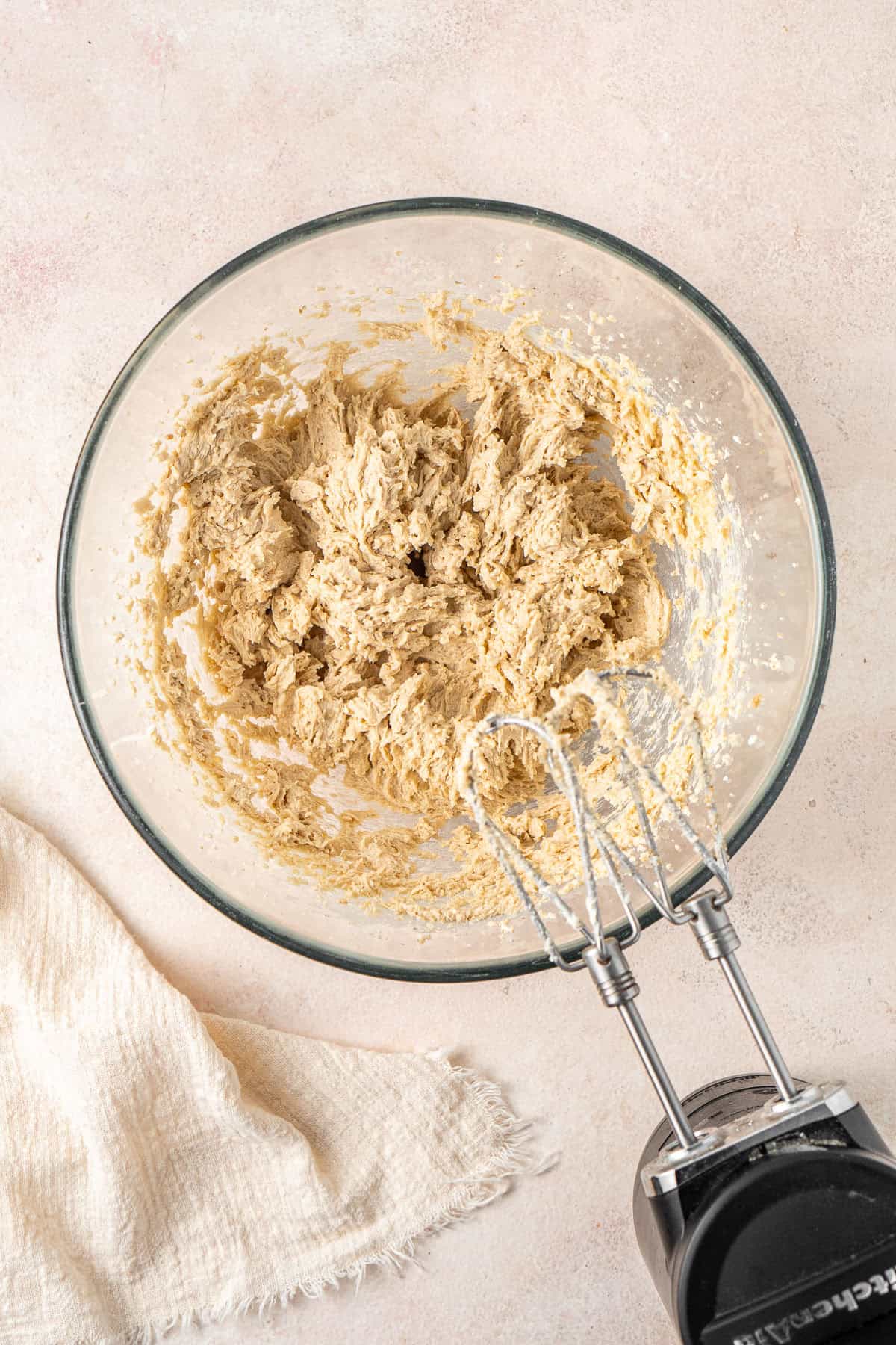 Beating together the butter and sugars in a glass bowl.