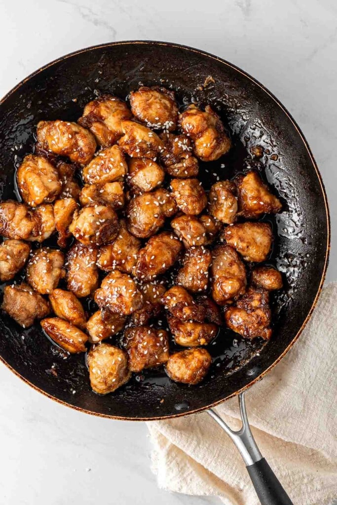 Chicken in a frying pan coated in honey soy sauce.