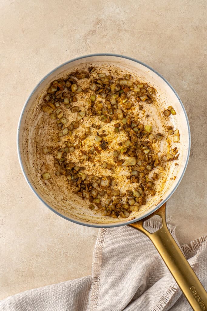 Sautéing the onion and spices in a frying pan.