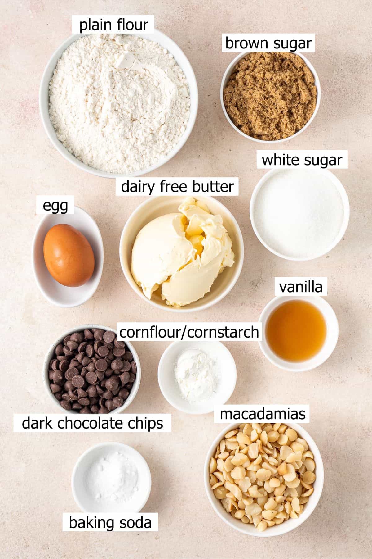 All ingredients needed to make dark chocolate macadamia cookies laid out in bowls.