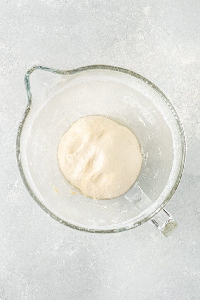 The smooth dough in a glass bowl before rising.