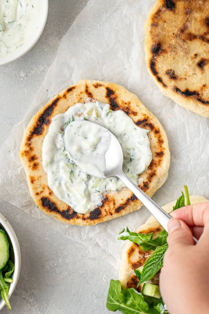 Spreading dairy free tzatziki onto the pita.