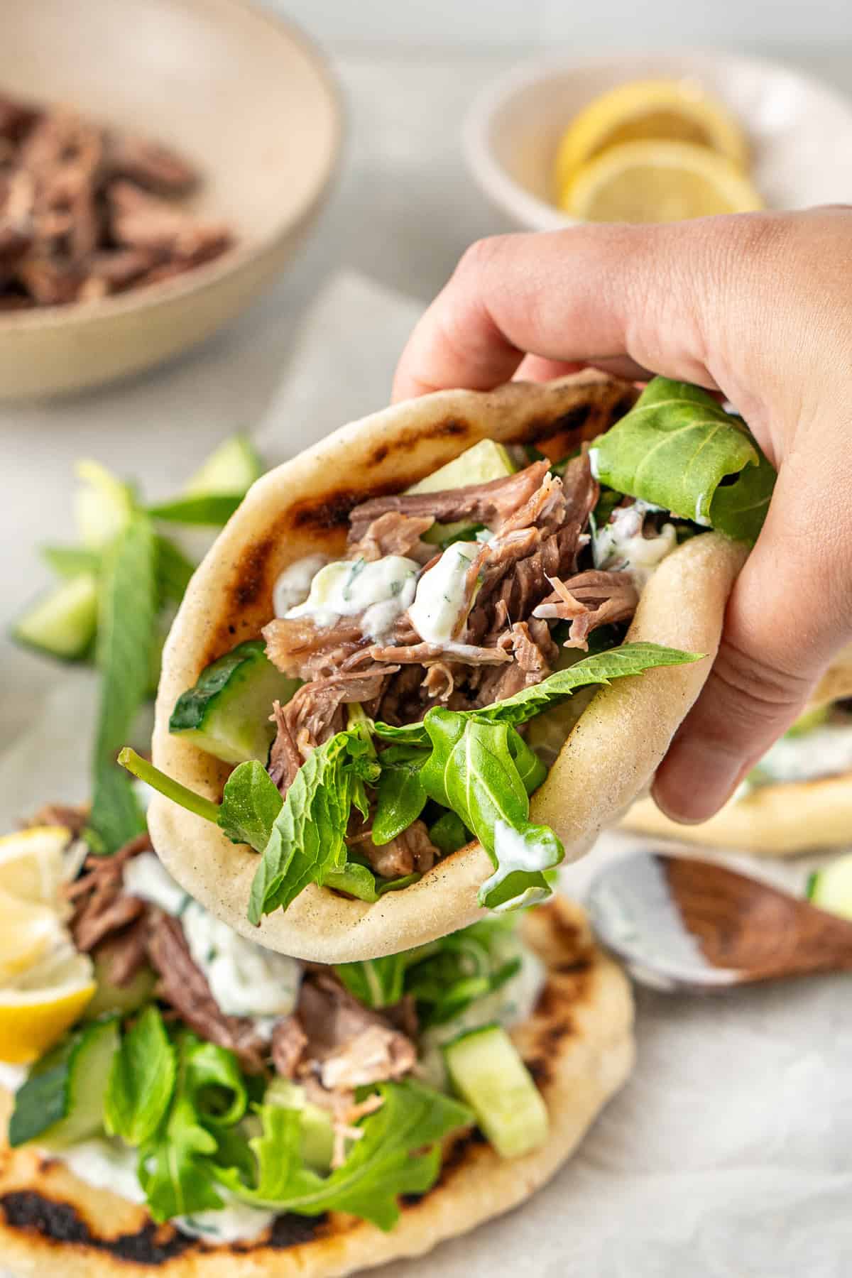 A hand picking up a lamb pita.