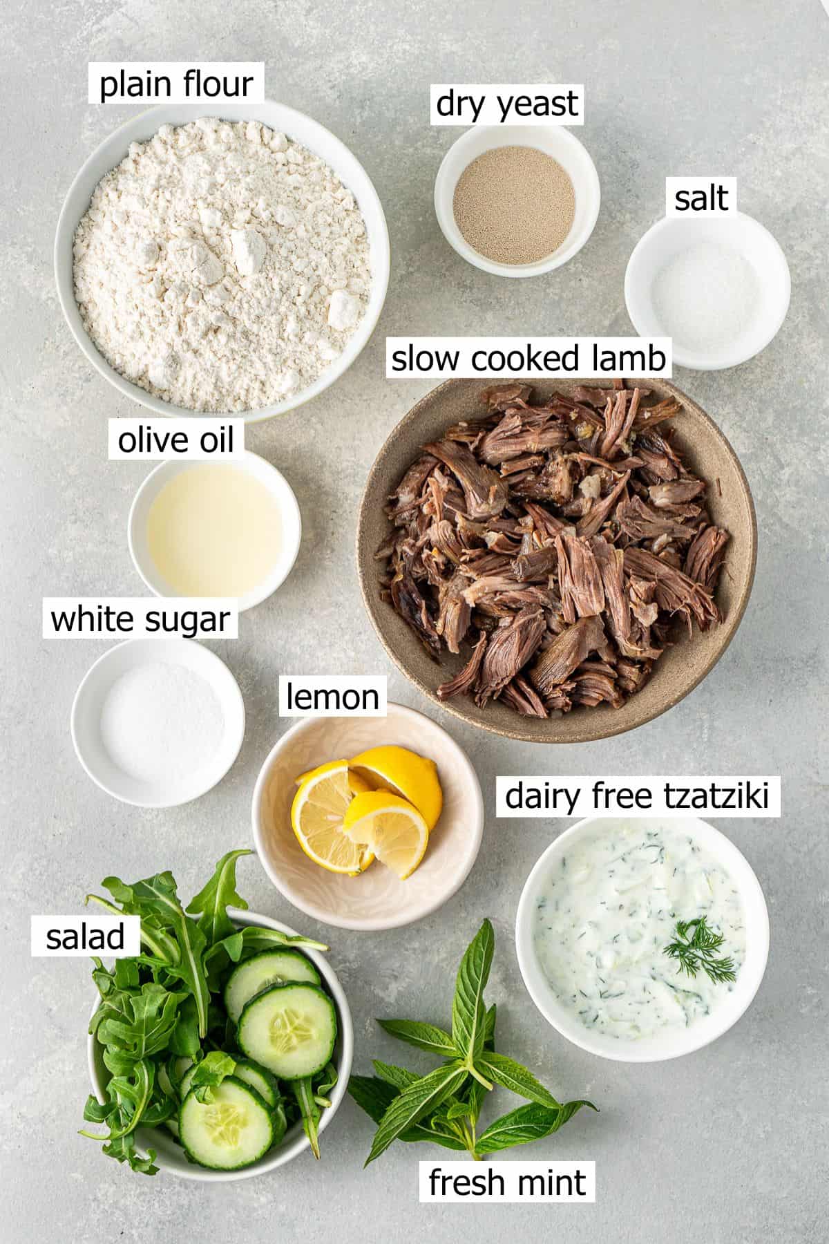 All ingredients needed to make greek lamb pitas laid out in bowls.