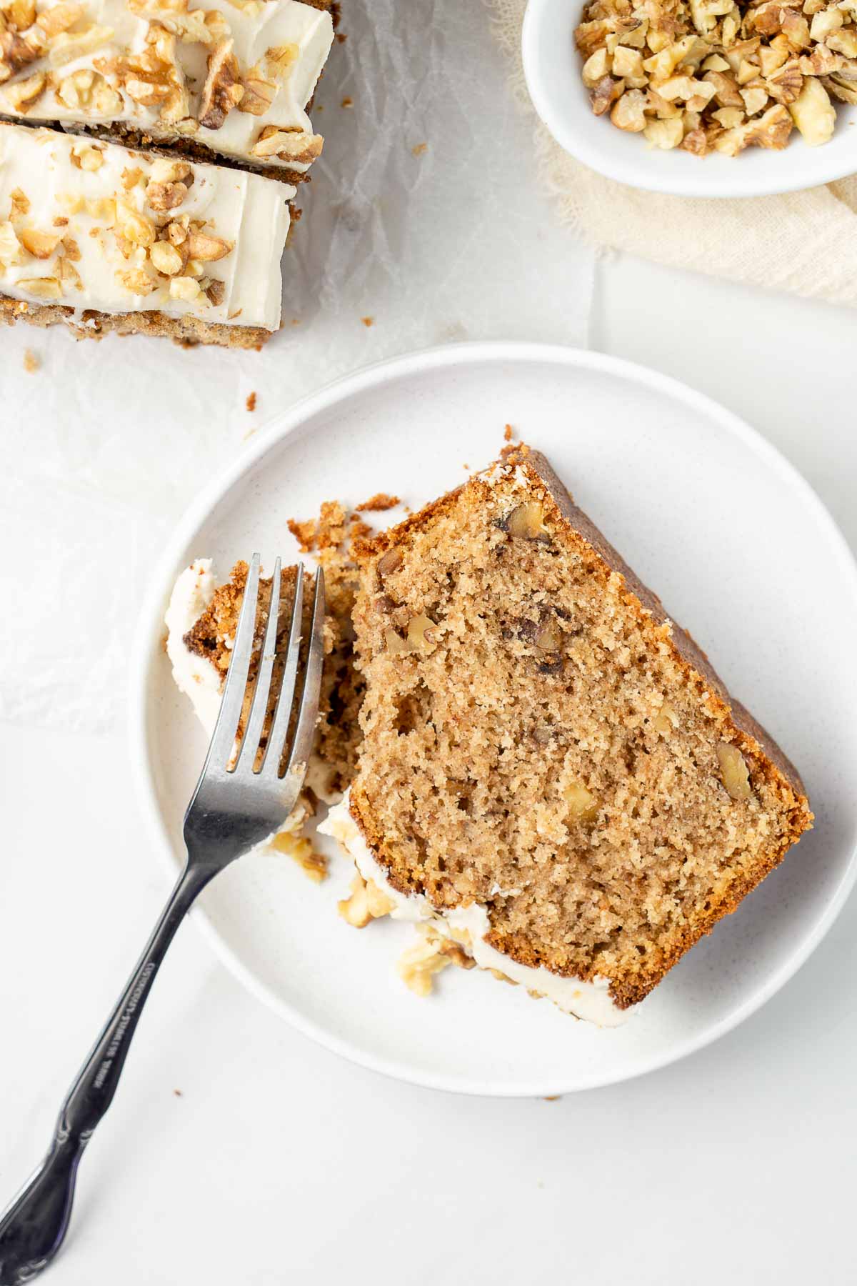 Slice of coffee walnut cake on a white plate with a fork.