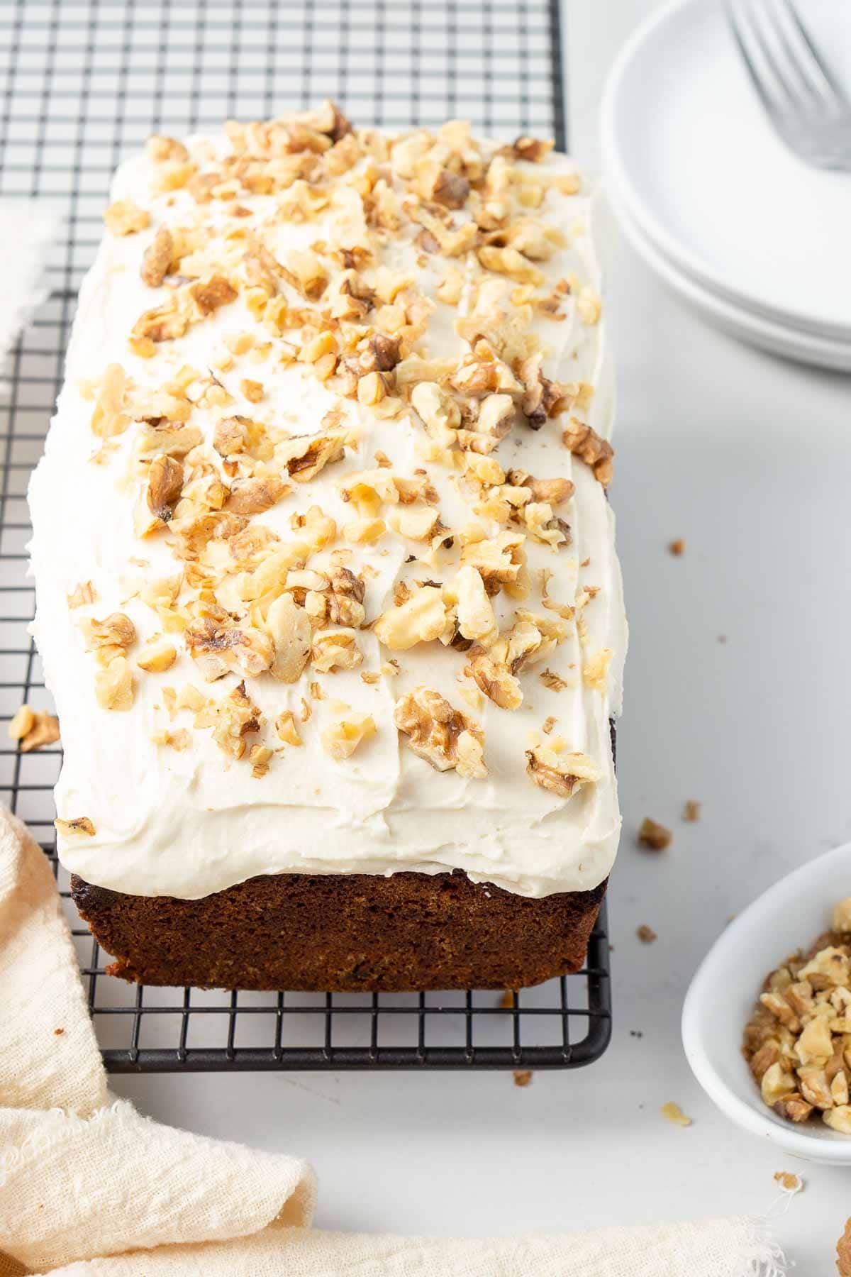 Coffee and walnut loaf cake on a wire cooling rack topped with coffee icing and chopped walnuts.