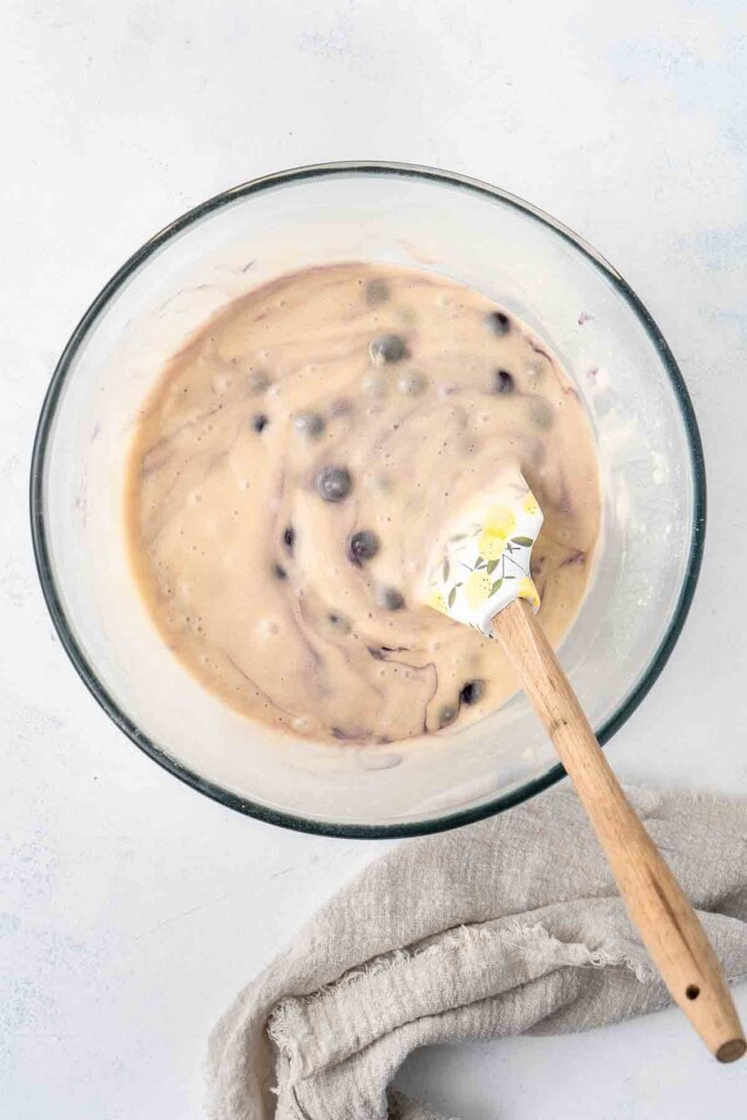 Blueberry muffin batter in a bowl with a spatula. 