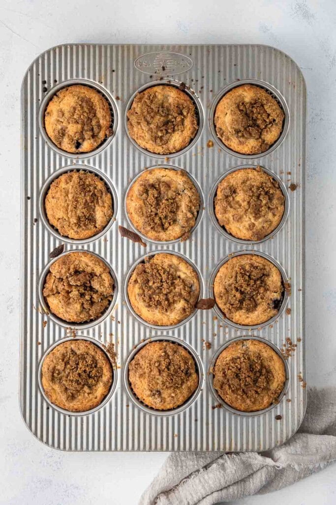 Blueberry earl grey muffins with a crumble topping in a muffin pan.