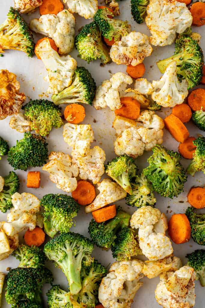 Close up of the broccoli, cauliflower and carrot on a baking tray.