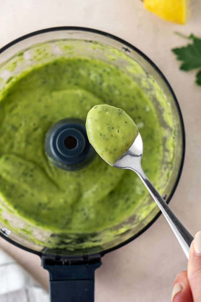 A spoon with the green goddess sauce from the food processor.