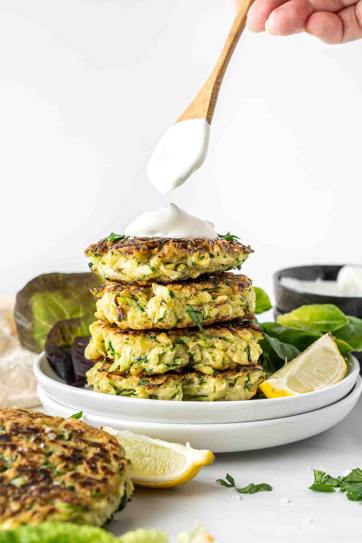 Dolloping sour cream on top of zucchini fritters.