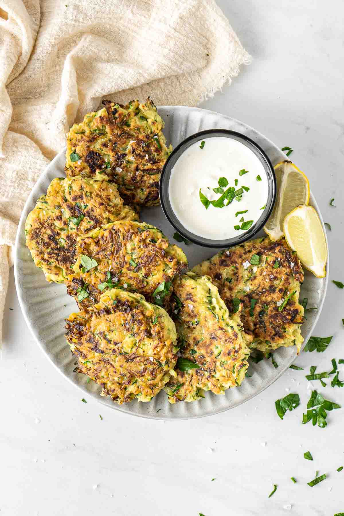 Zucchini fritters on a plate with sauce and lemon.