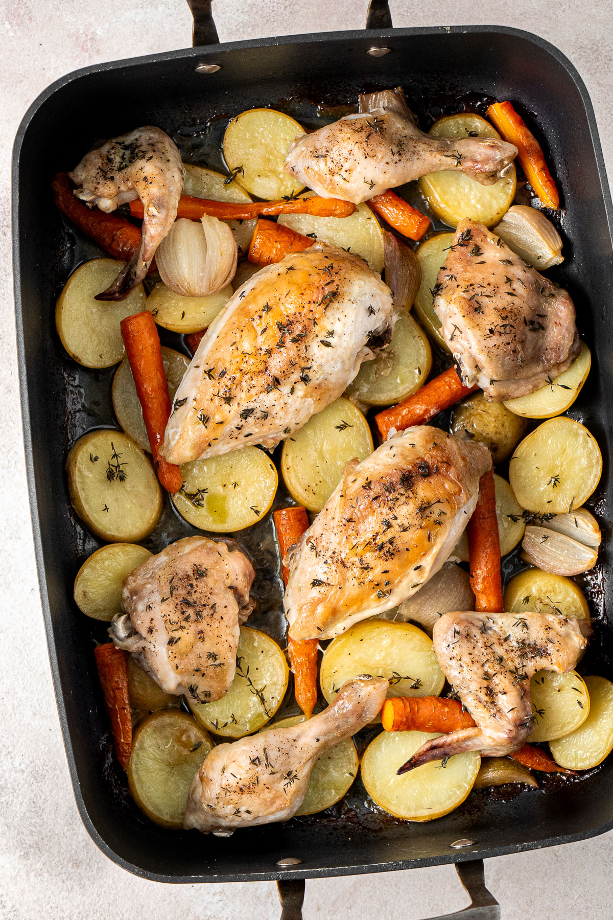 Roast chicken and vegetables in a roasting pan.