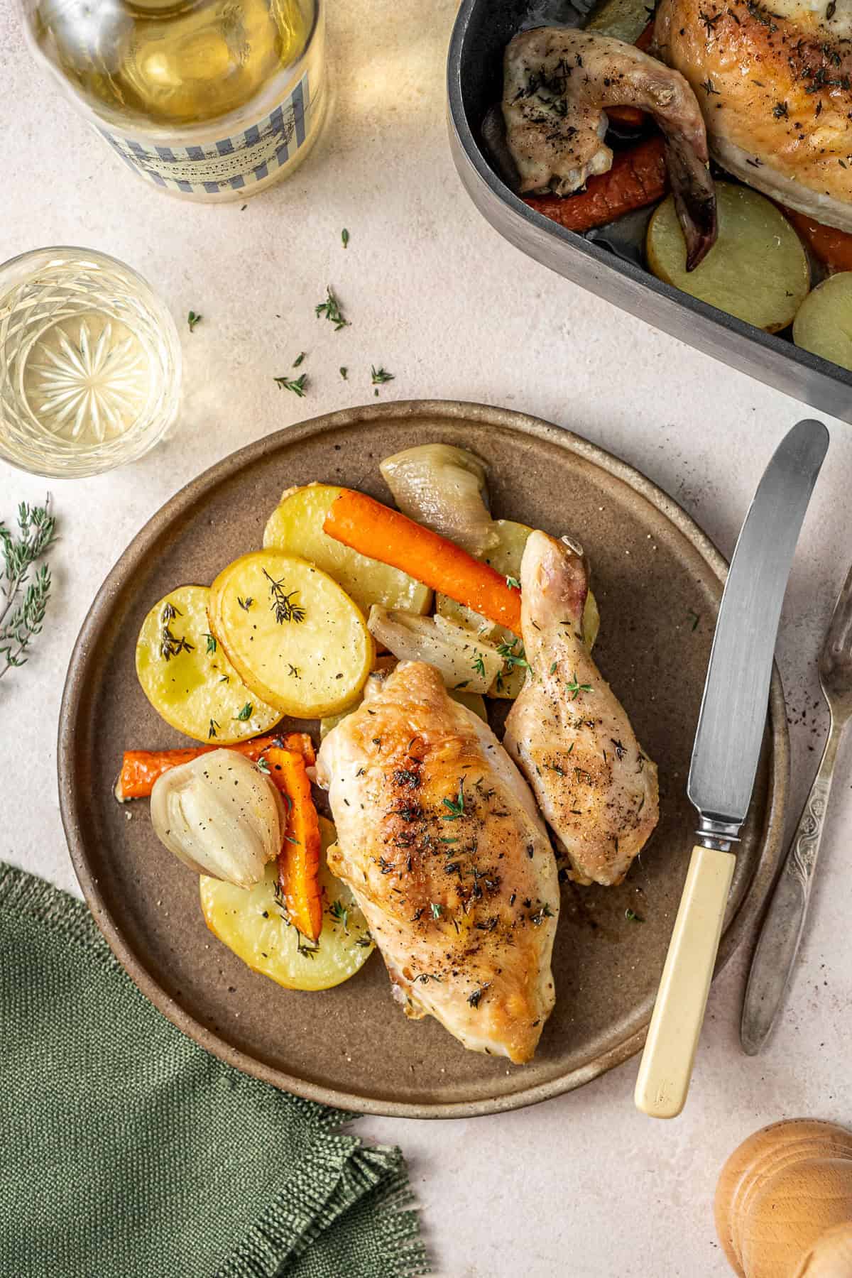 The portions of roast chicken plated with the vegetables and a glass of wine.