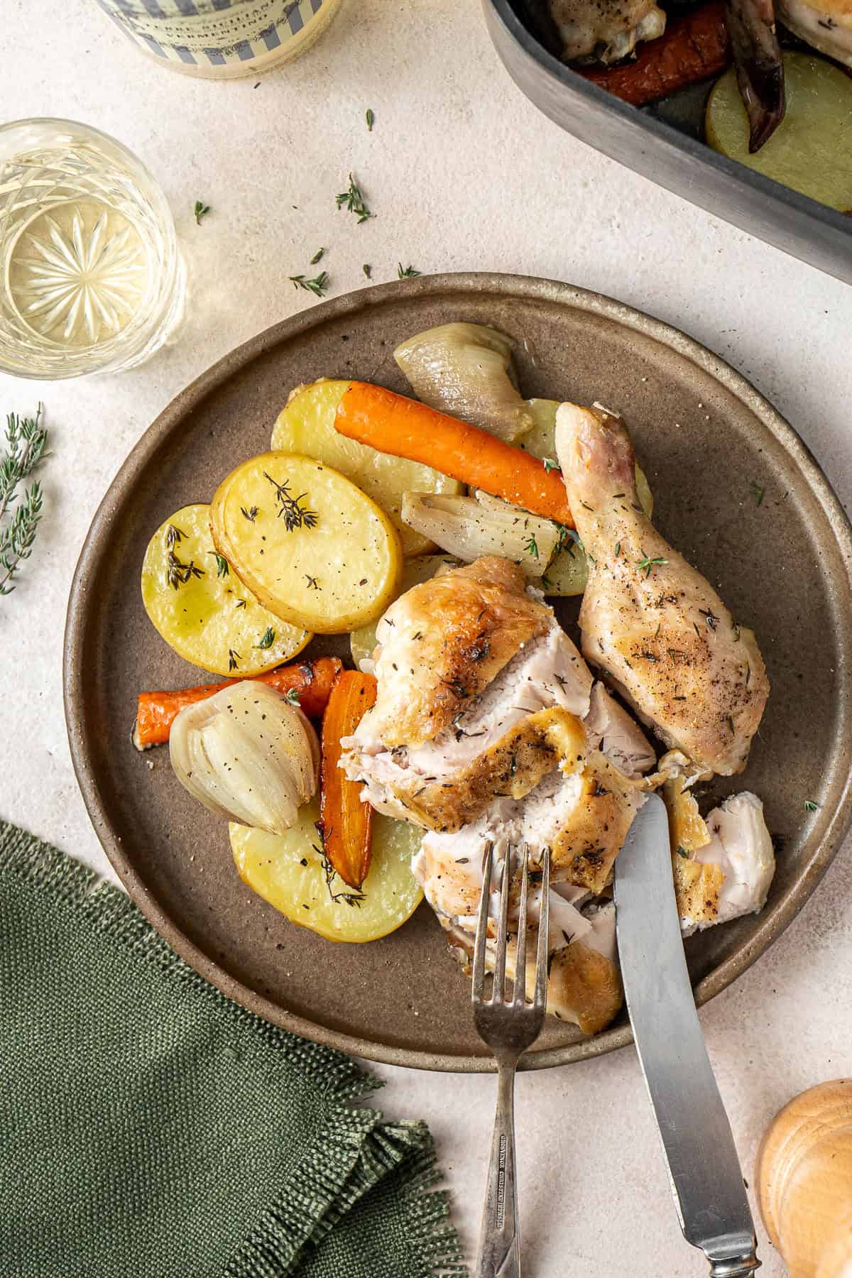 The roast chicken cut into pieces with vegetables on a plate.
