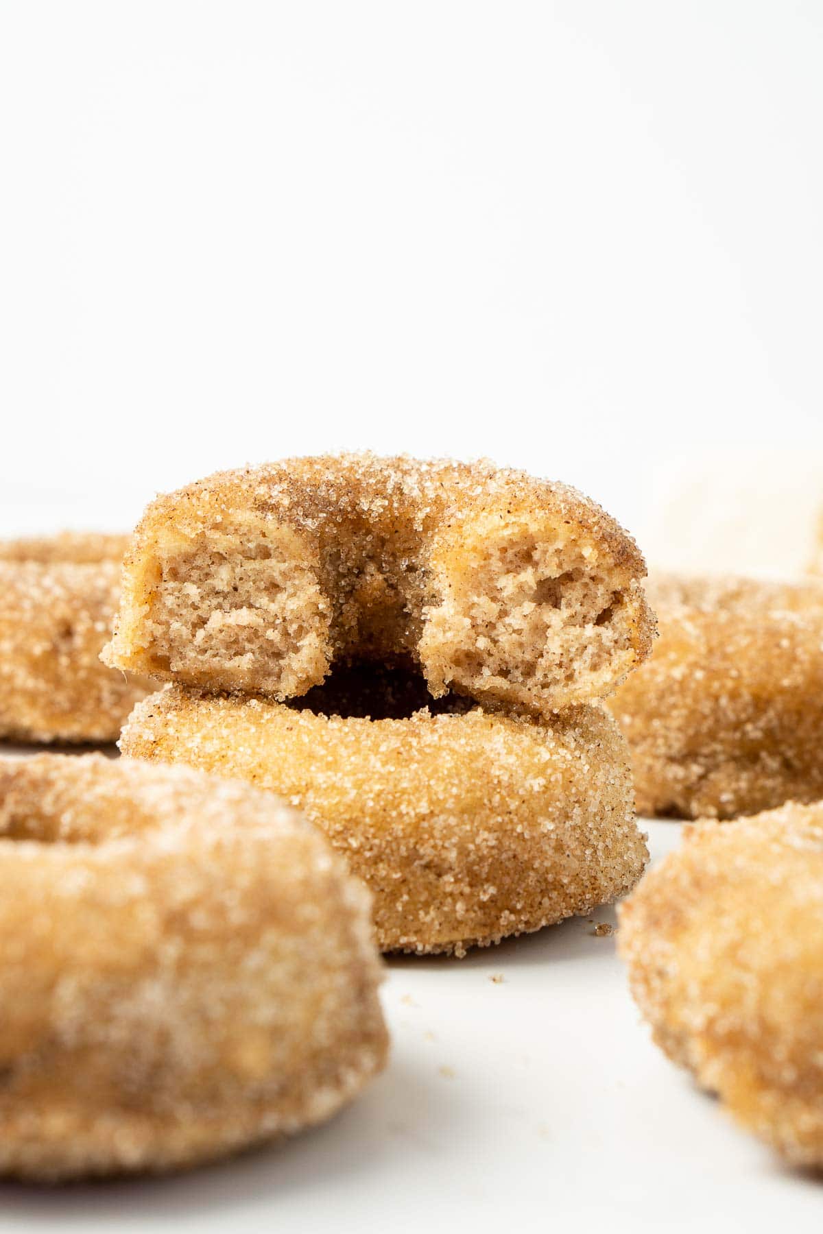 Baked cinnamon sugar doughnuts stacked on top of each other, one with a bite taken.
