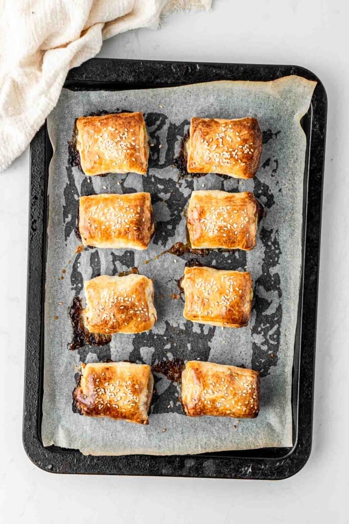 Classic sausage rolls on a baking tray fresh from the oven.
