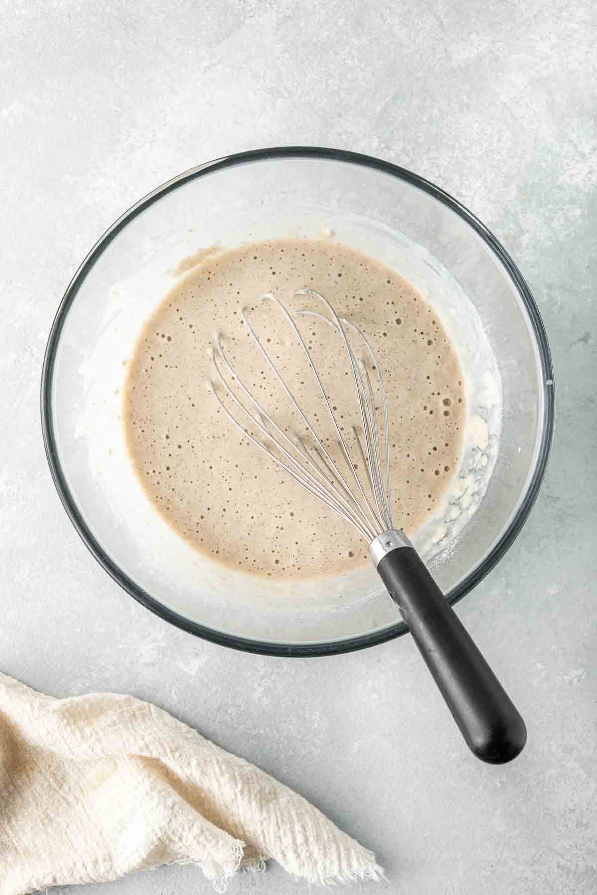 The pancake batter in a bowl with a whisk.