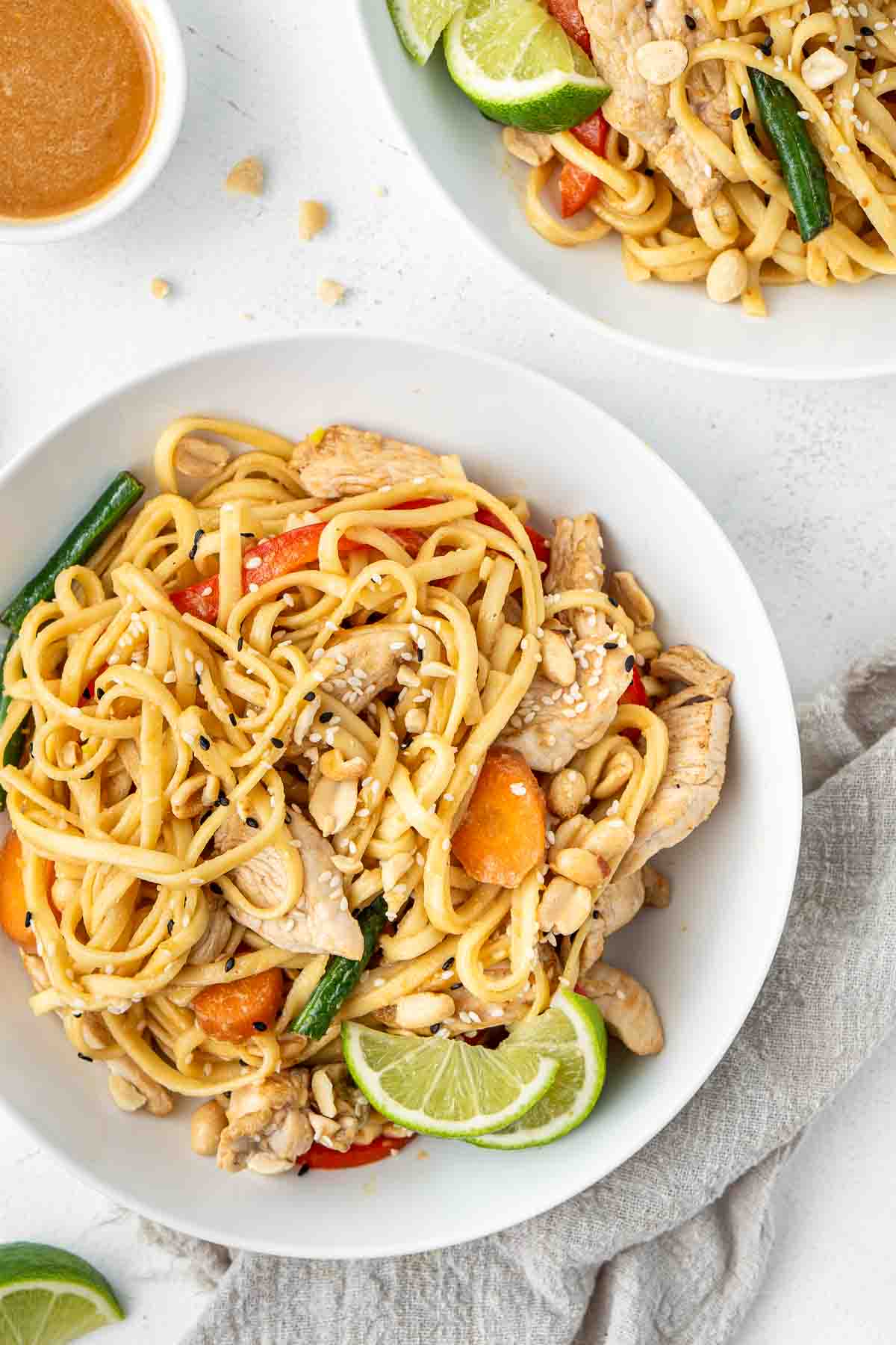 Chicken satay noodles in white bowls.