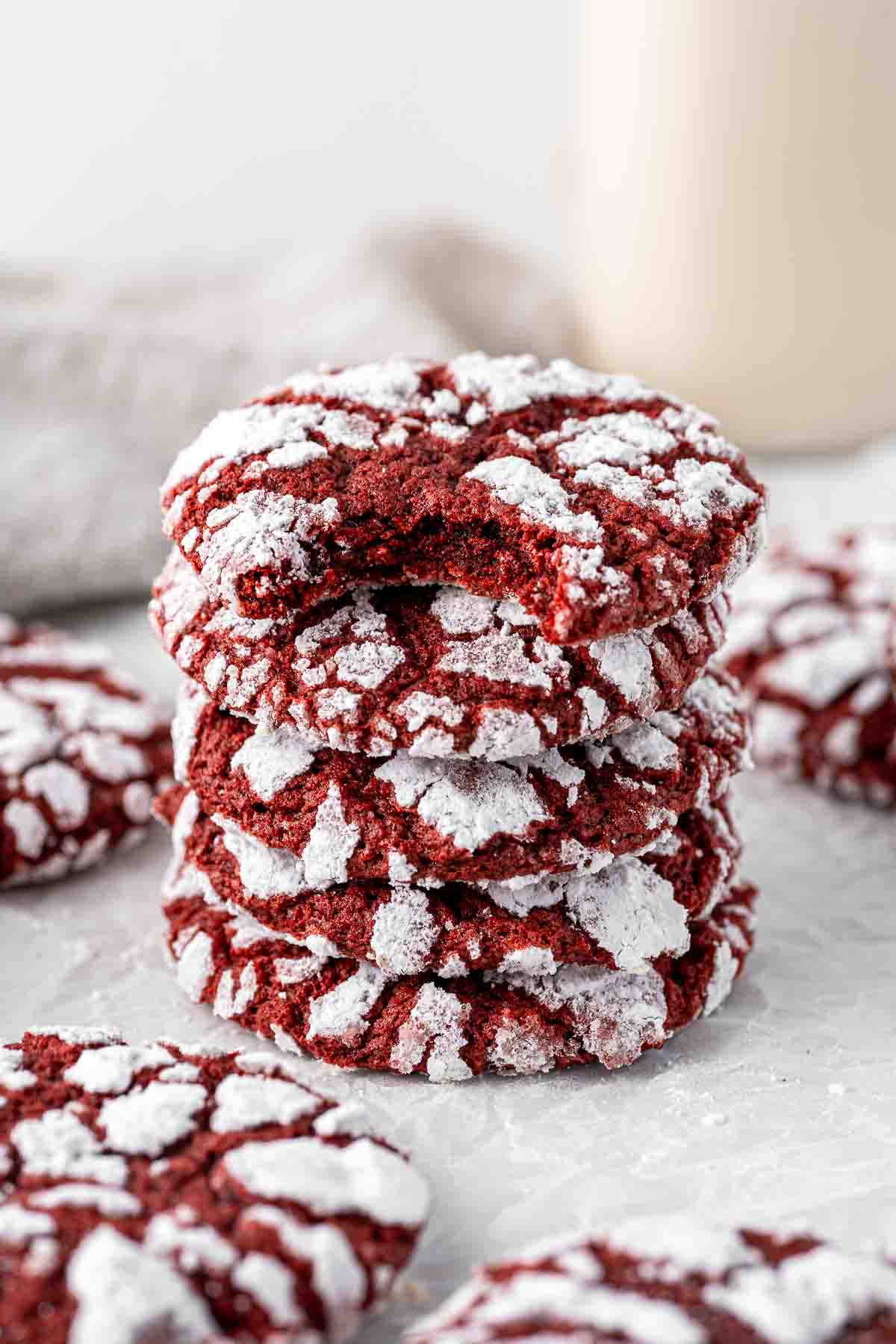 Stack of red velvet crinkle cookies with a bite taken from the top one.