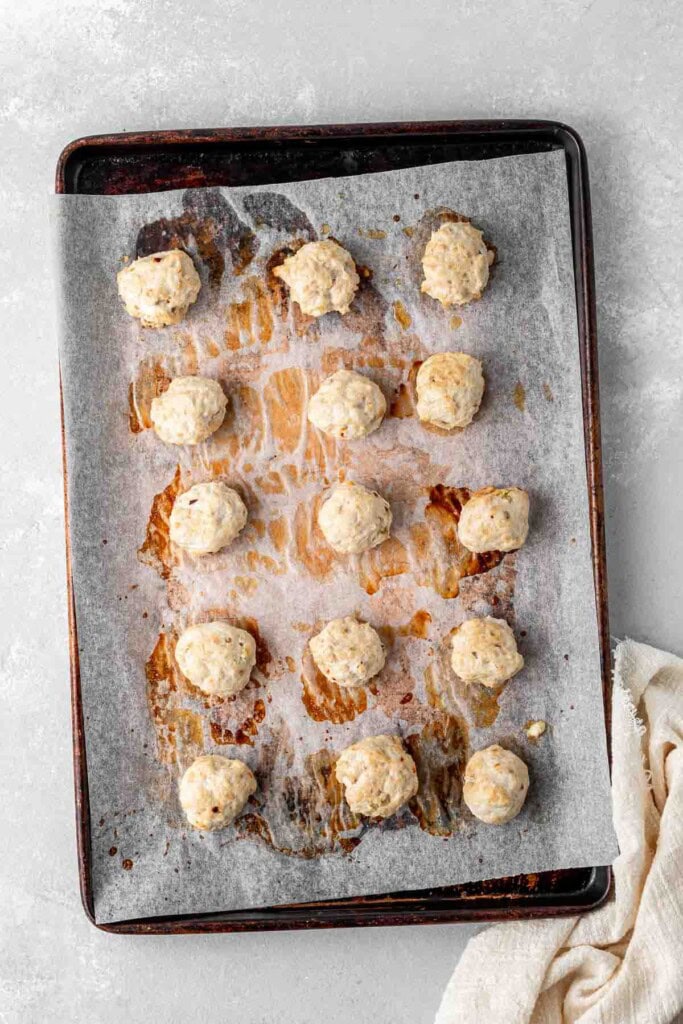 Baked chicken meatballs on a baking tray.