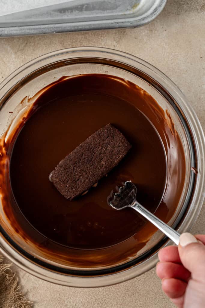 Dunking the biscuit in the melted chocolate. 