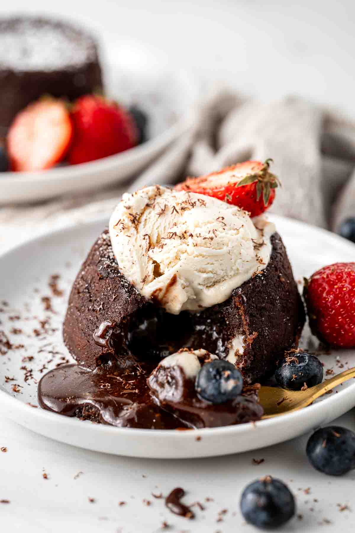 Chocolate lava cake with ice cream and berries and a gold spoon.